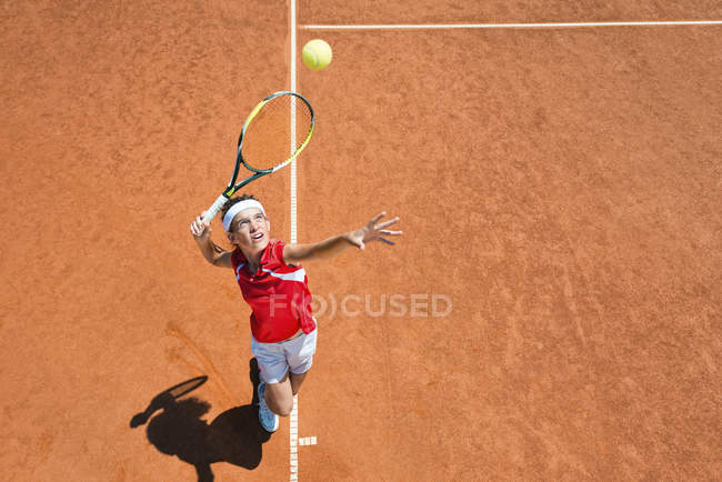 Jugadora de tenis sirviendo pelota en la cancha . - foto de stock