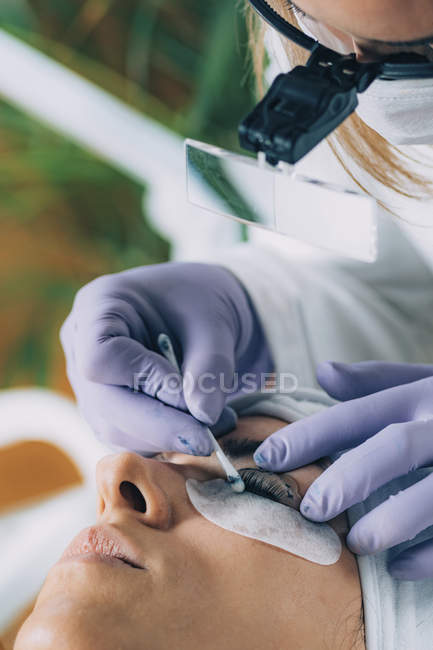 Cosmetologist cleaning patient eyes after lash lifting procedure — Stock Photo
