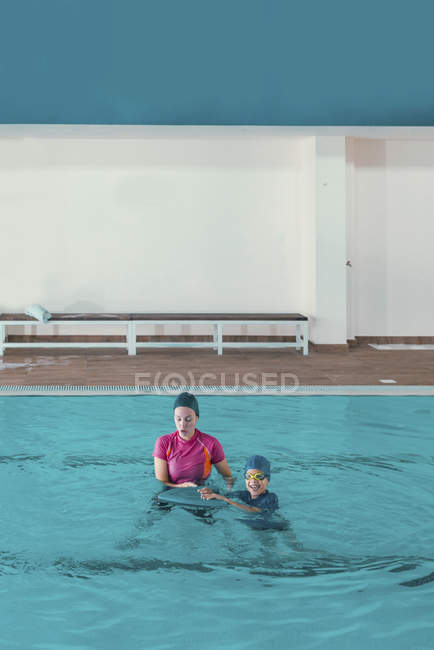 Niño en clase de natación con instructor en piscina . - foto de stock