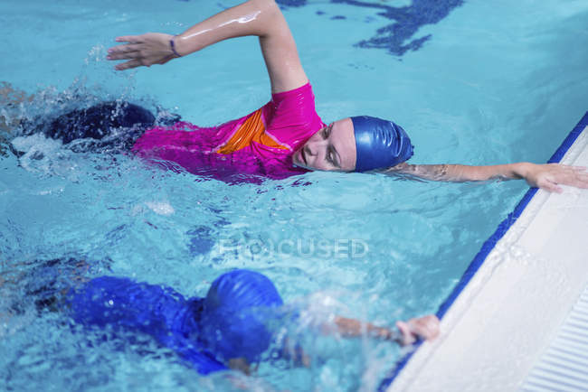 Carino bambino imparare a nuotare con istruttore femminile in piscina . — Foto stock