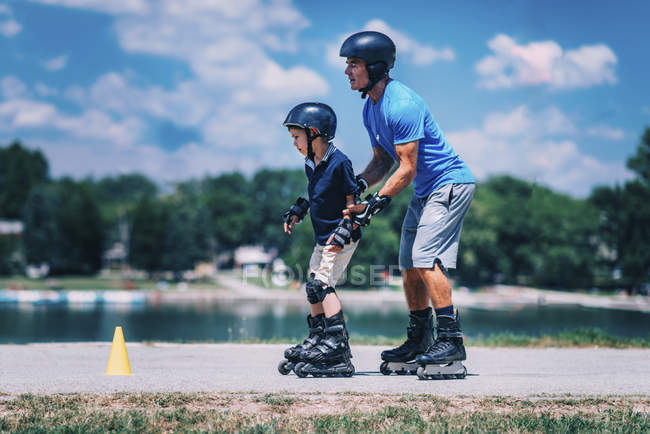 Professeur principal de patin à roulettes avec garçon pratiquant en classe dans le parc . — Photo de stock