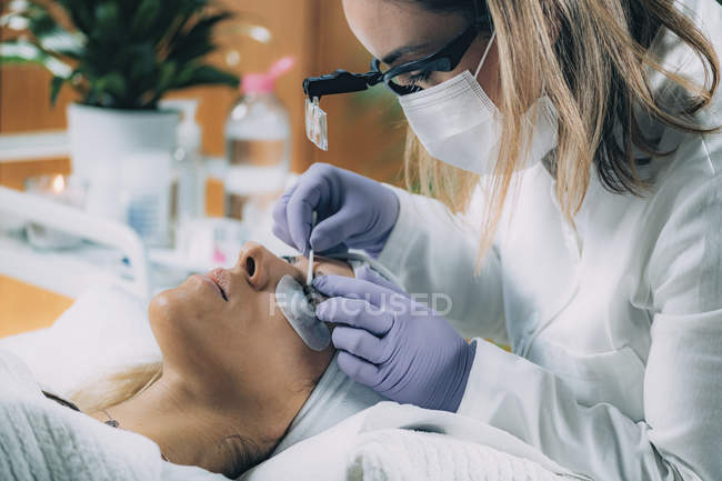Cosmetologista limpando os olhos do paciente após o procedimento de elevação das pestanas — Fotografia de Stock