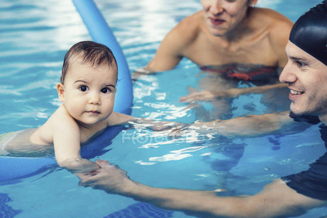 Instructor con bebé y madre practicando en la piscina . - foto de stock
