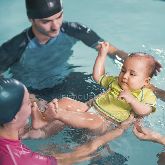 Baby having swimming class with instructors in swimming pool. — Stock Photo