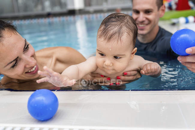 Instructor con bebé y madre jugando en la piscina . - foto de stock