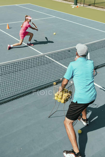 Instrutor de tênis masculino treinando adolescente jogadora na quadra . — Fotografia de Stock