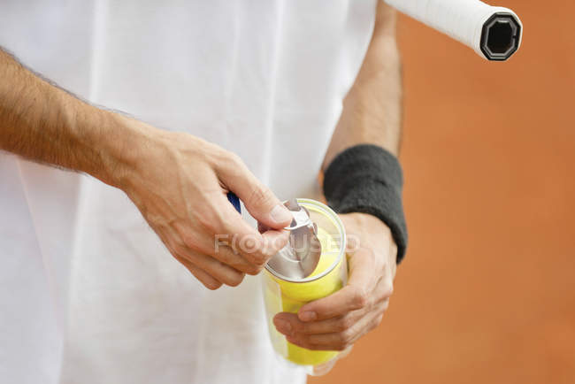 Nahaufnahme eines Tennisspielers, der eine neue Packung Bälle öffnet. — Stockfoto
