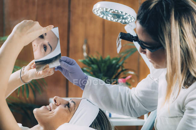 Satisfied patient after lash lifting procedure looking into mirror — Stock Photo