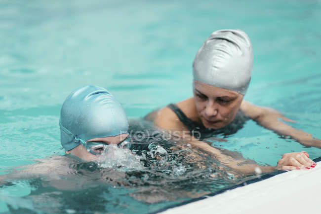 Istruttore di nuoto che lavora con il bambino in piscina . — Foto stock