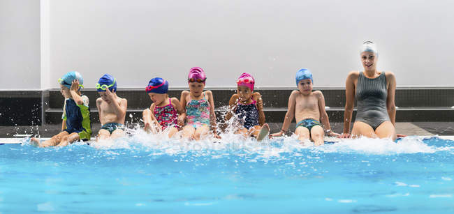 Инструктор по плаванию развлекается с группой маленьких детей в бассейне . — стоковое фото