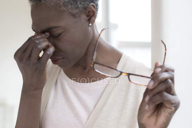 Mujer madura con dolor de cabeza tensión sosteniendo gafas
. - foto de stock