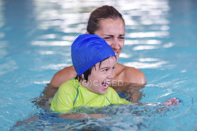 Menino tendo aula de natação com instrutora feminina na piscina . — Fotografia de Stock