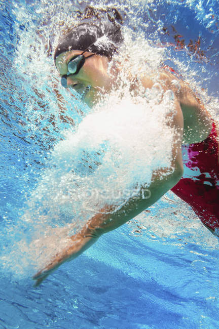 Underwater view of female swimmer in public swimming pool water. — Stock Photo