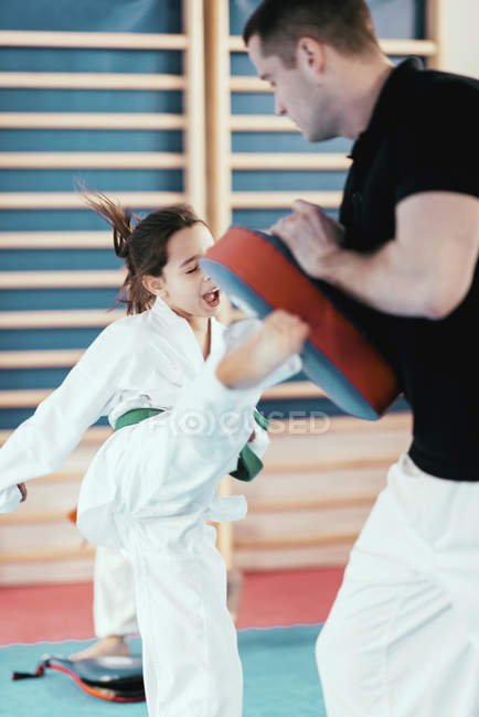 Menina chutando na aula de taekwondo com treinador . — Fotografia de Stock