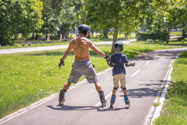 Junge lernt Rollschuhlaufen mit Opa im Park. — Stockfoto