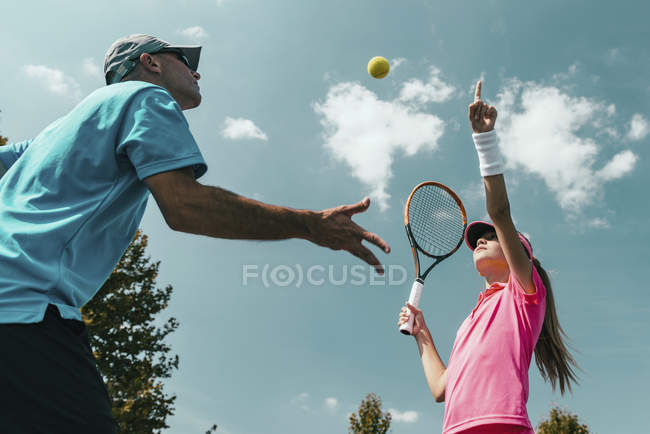 Male tennis instructor training teenage female player on court. — Stock Photo