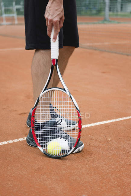 Low section of tennis player picking ball with racket. — Stock Photo