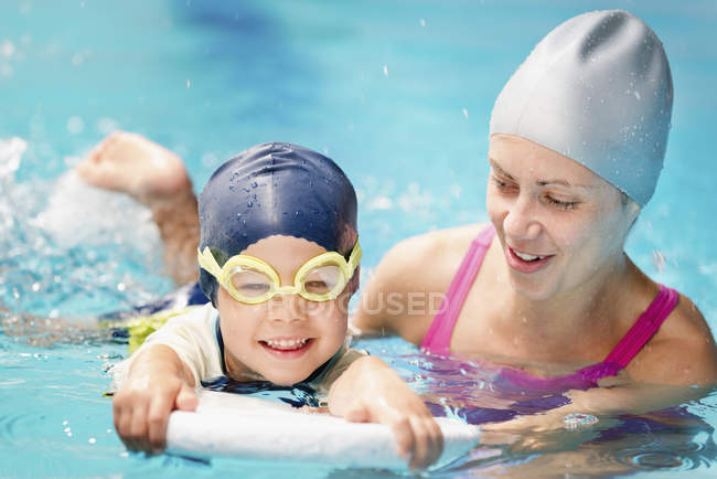 Menino aprendendo a nadar com instrutora na piscina . — Fotografia de Stock