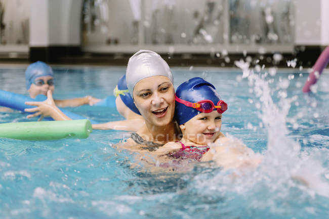 Instruktorin arbeitet mit kleinem Mädchen im Schwimmbad. — Stockfoto