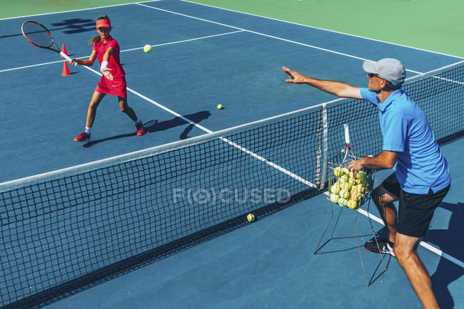 Teen girl in tennis training on court with male instructor. — Stock Photo