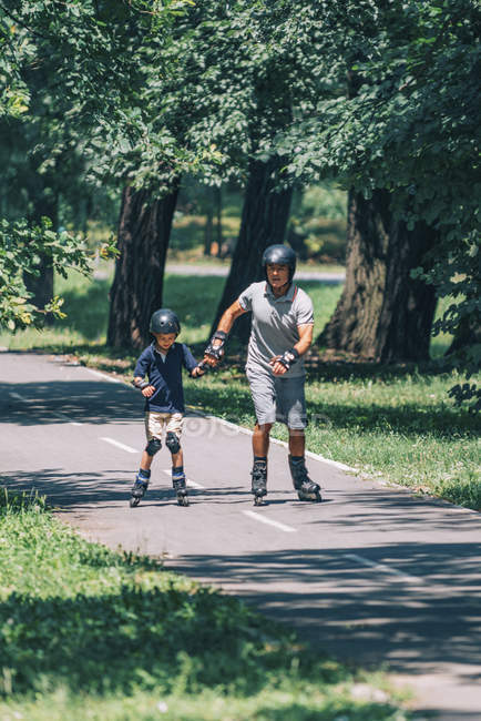 Дедушка и внук наслаждаются катанием на роликах в летнем парке . — стоковое фото