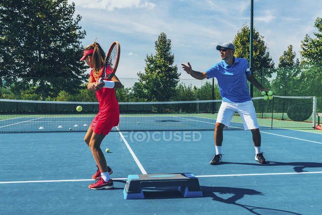 Adolescent tennis player practicing with male instructor in tennis class. — Stock Photo