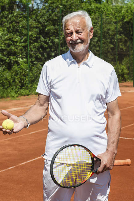 Retrato de tenista sênior ativo sorrindo e olhando para a câmera . — Fotografia de Stock