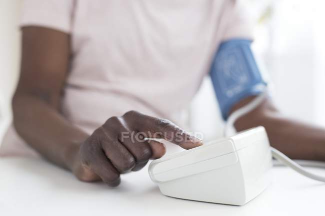 Reife Frau testet Blutdruck mit Maschine. — Stockfoto