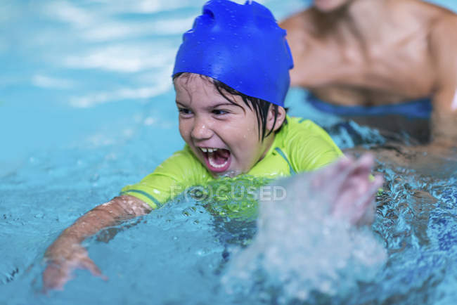 Ragazzino che fa lezione di nuoto con istruttrice femminile in piscina . — Foto stock