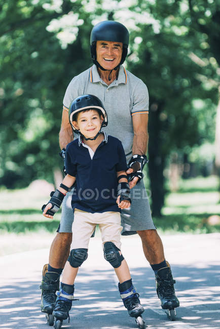 Nonno e nipote godendo pattinaggio nel parco estivo . — Foto stock