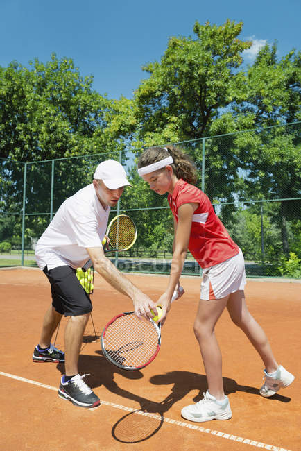 Instrutor de tênis trabalhando com jogador adolescente em serviço . — Fotografia de Stock