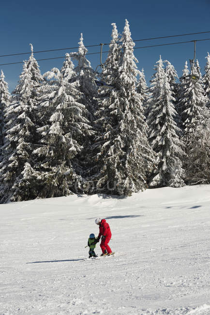 Menino e instrutor de esqui esqui nas montanhas . — Fotografia de Stock