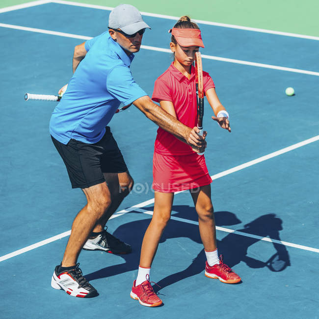 Adolescente em treinamento de tênis na quadra com instrutor masculino . — Fotografia de Stock