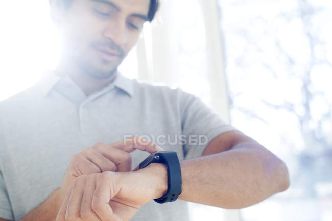 Man checking smartwatch on wrist in backlit. — Stock Photo