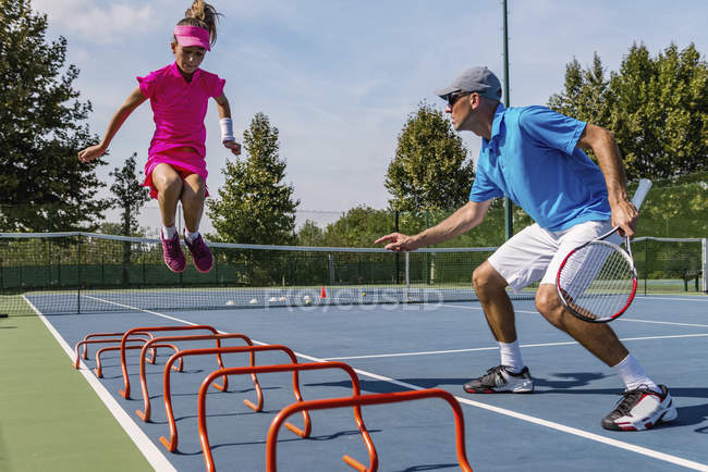 Chica adolescente en el entrenamiento de tenis en la cancha con instructor masculino . - foto de stock