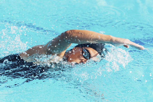 Woman swimming front crawl style in swimming pool. — Stock Photo