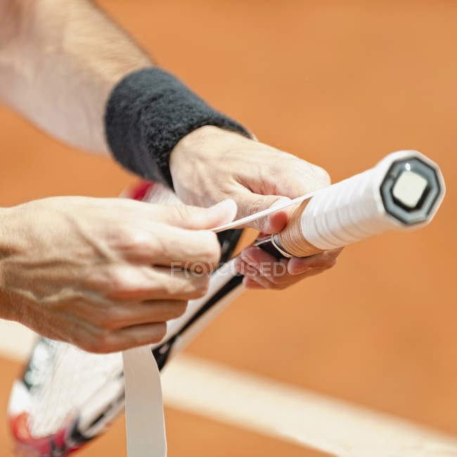 Gros plan des mains des joueurs enveloppant le nouveau ruban adhésif sur la raquette de tennis . — Photo de stock