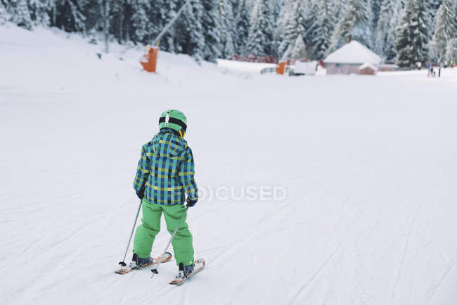 Niño con ropa de invierno esquiando en las montañas nevadas . - foto de stock