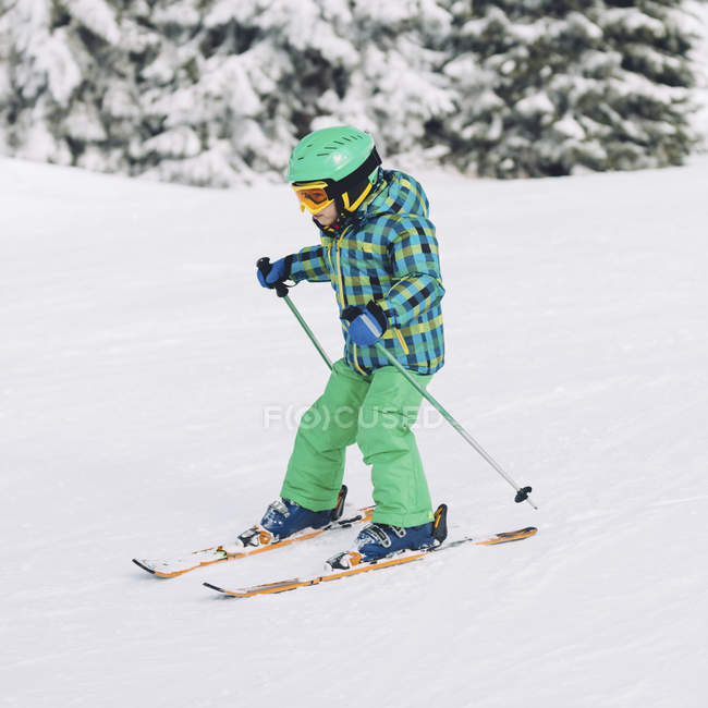Niño con ropa de invierno esquiando en las montañas nevadas . - foto de stock