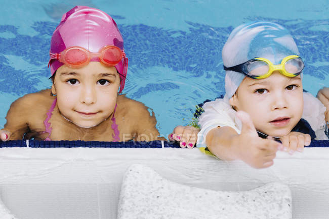 Cute boy and girl in public swimming pool. — Stock Photo
