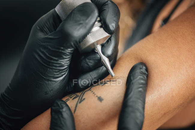 Mestre tatuando pele feminina em detalhes, imagem tonificada . — Fotografia de Stock