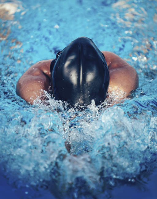 Breaststroke swimmer splashing water in pool. — Stock Photo