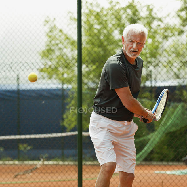 Male senior player practicing tennis on court. — Stock Photo