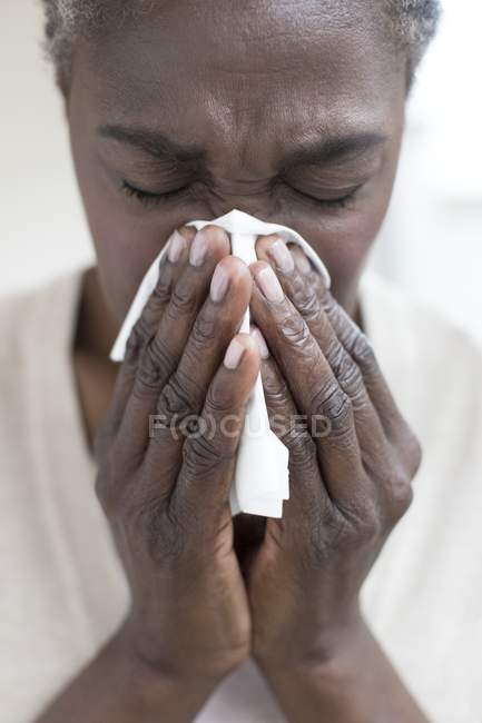 Primer plano de la mujer madura estornudando en el tejido
. - foto de stock