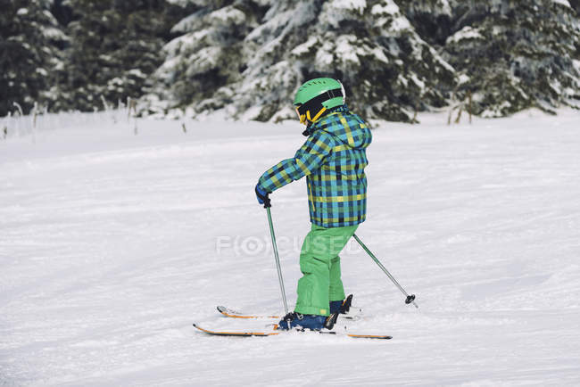 Menino em roupas de inverno esquiando em montanhas nevadas . — Fotografia de Stock
