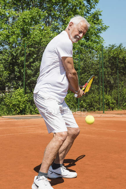 Uomo anziano che gioca a tennis sul campo . — Foto stock