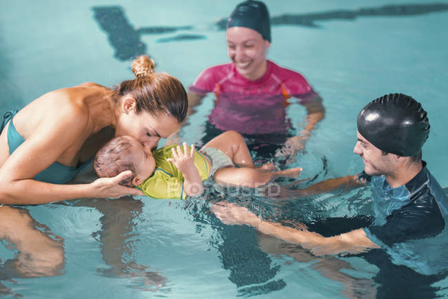 Mulher com filho tendo bebê aula de natação com instrutores em piscina . — Fotografia de Stock