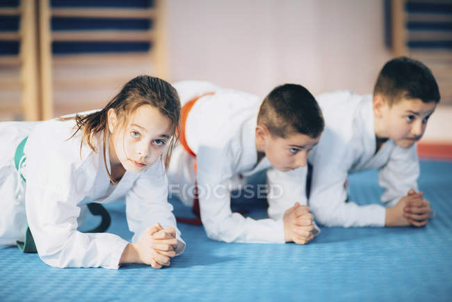 Тренировка детей на коврике в классе тхэквондо . — стоковое фото