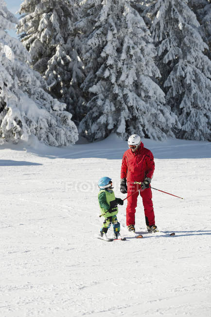Aula de esqui com instrutor masculino e menino em montanhas nevadas . — Fotografia de Stock