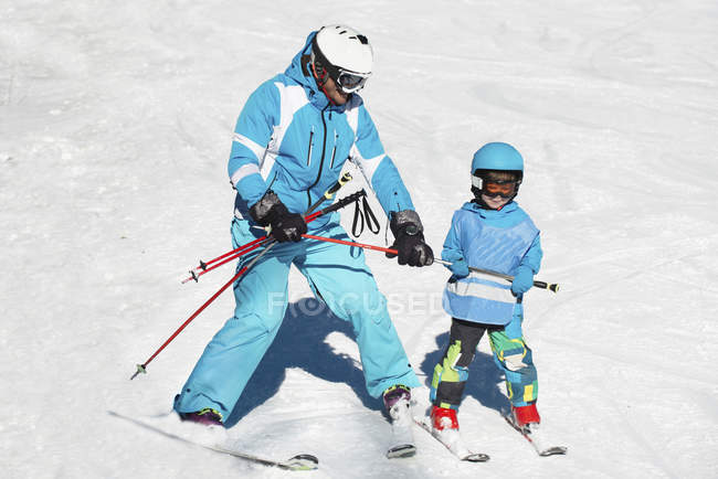 Menino da idade elementar tendo aula de esqui com o pai . — Fotografia de Stock